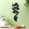 Black silhouette of a dragon wall art mounted on a light green wall next to white flowers and a donut.