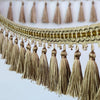 Golden decorative tassel fringe trim with a beige border and multiple tassels hanging from it.