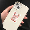 A hand holds a light beige smartphone displaying a watercolor illustration of a pink pig.