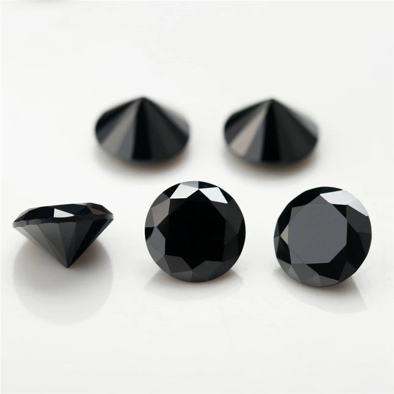 Three black round cut cubic zirconia stones of varying sizes displayed on a white surface.