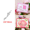 A silver floral love word stencil and stamp set displayed on a pink background with roses and greenery.