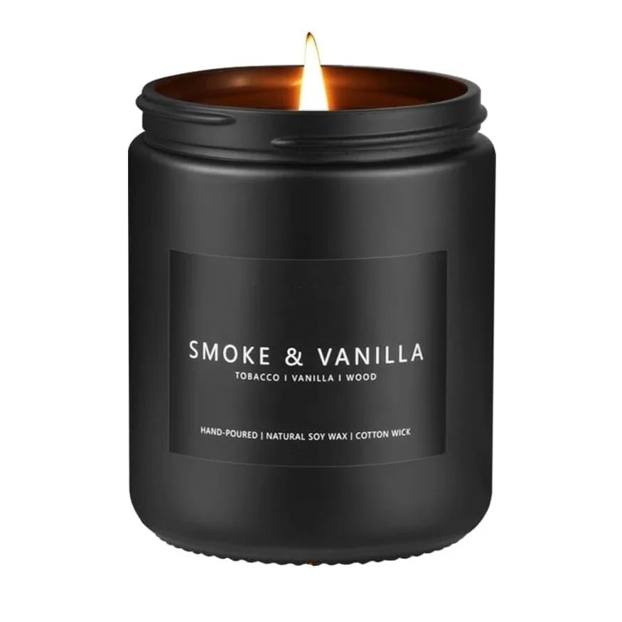 A black jar candle with a lit wick, labeled Smoke & Vanilla Tobacco and Vanilla I Wood.