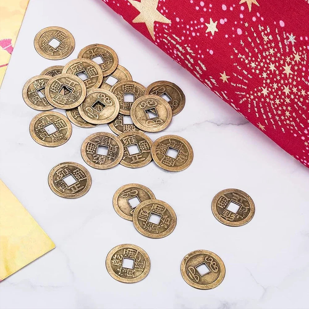 A pile of antique Chinese Feng Shui coins scattered on a white marble surface next to a red fabric.