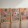 Tres estampas florales botánicas enmarcadas con flores y follaje colorido en marcos de madera clara.