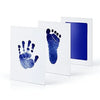 White framed print showing a blue handprint and footprint on the left, next to a larger blue footprint print.