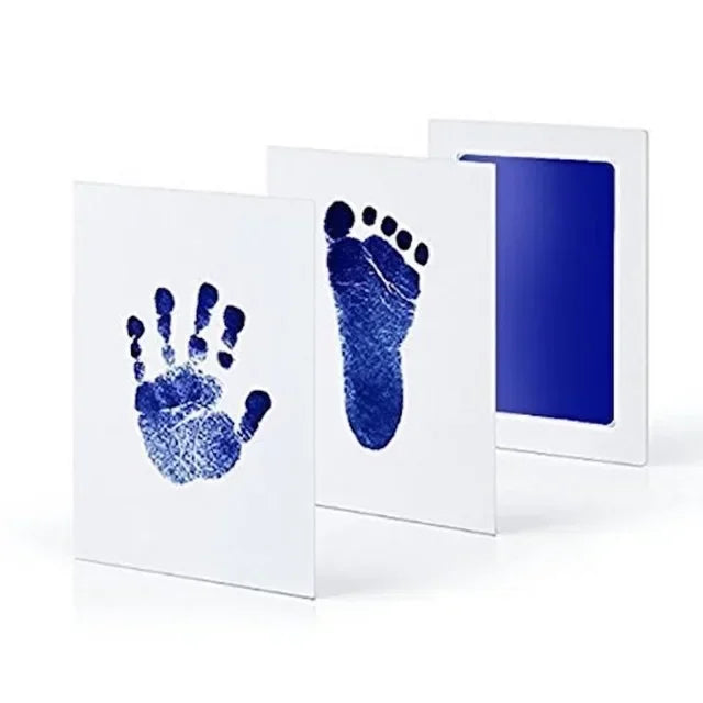 White framed print showing a blue handprint and footprint on the left, next to a larger blue footprint print.