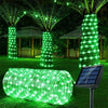 A coiled green LED rope light illuminates a garden scene with surrounding trees and structures.