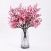 A bouquet of pink cherry blossom and gypsophila artificial flowers in a clear glass vase.