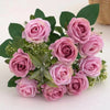 A bouquet of artificial pink and mauve roses with green leaves and small filler flowers.