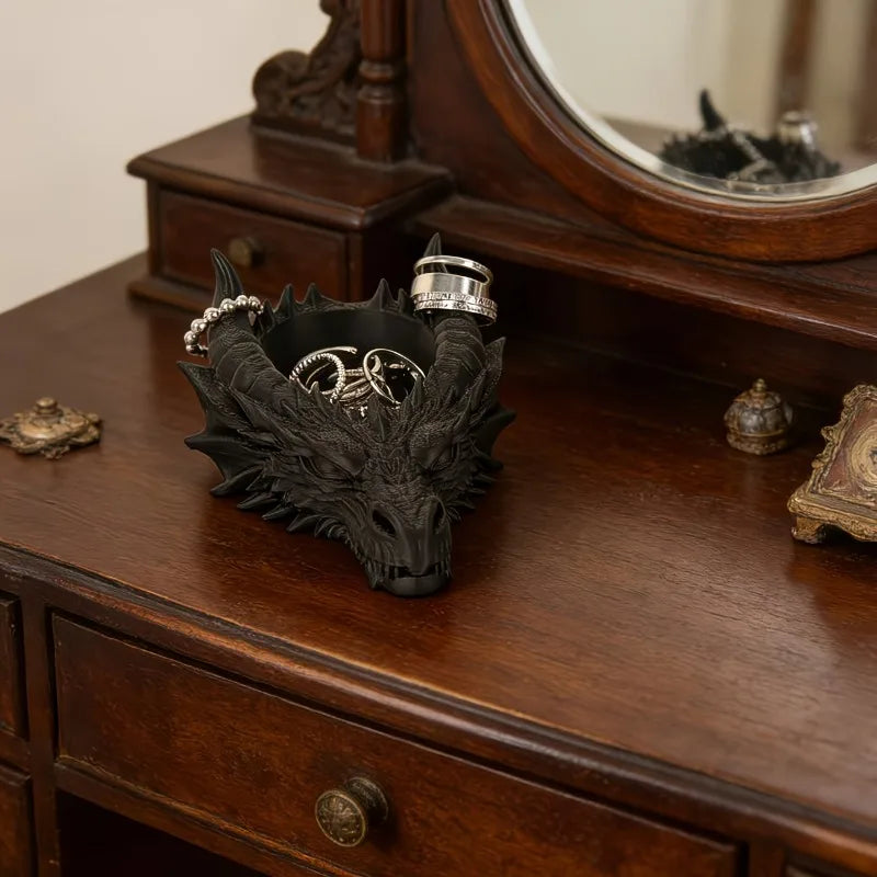 Pendentif de tête de dragon noir avec des anneaux d'argent sur un bureau en bois sombre.