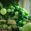 A lush green balloon garland arch display featuring various shades of lime and forest green balloons.