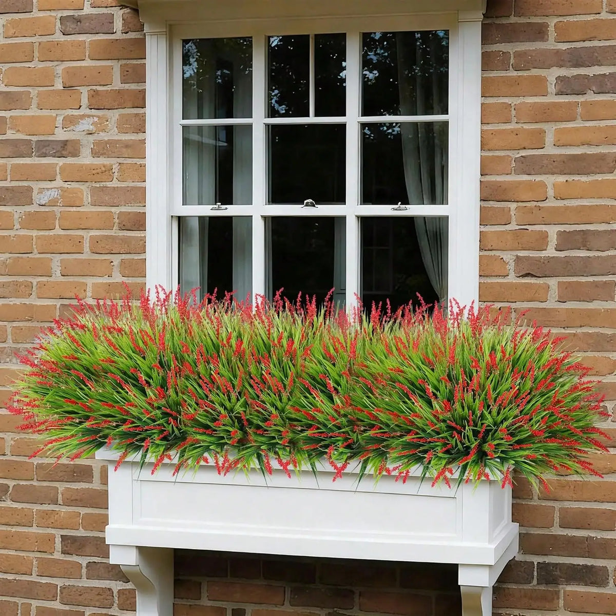 A vibrant green and red artificial lavender wreath in a white planter box mounted on a brick wall.