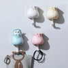 Three pastel-colored cartoon cat wall hooks in various sizes and styles for organization