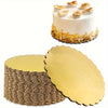 A white layer cake decorated with toasted coconut, next to a stack of round gold disposable cake plates.