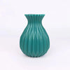 A teal ceramic flower vase with vertical fluting and a flared rim.