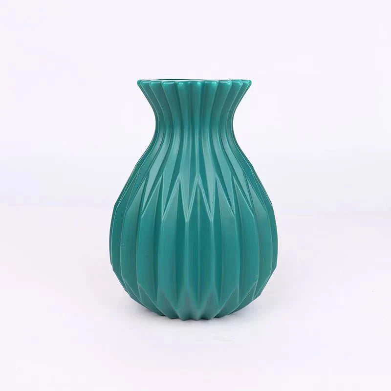 A teal ceramic flower vase with vertical fluting and a flared rim.