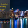 High resolution night view of the New York City skyline with illuminated buildings reflected on the water.