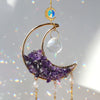 A gold moon-shaped crystal suncatcher featuring purple amethyst crystals and a blue rainbow prism.