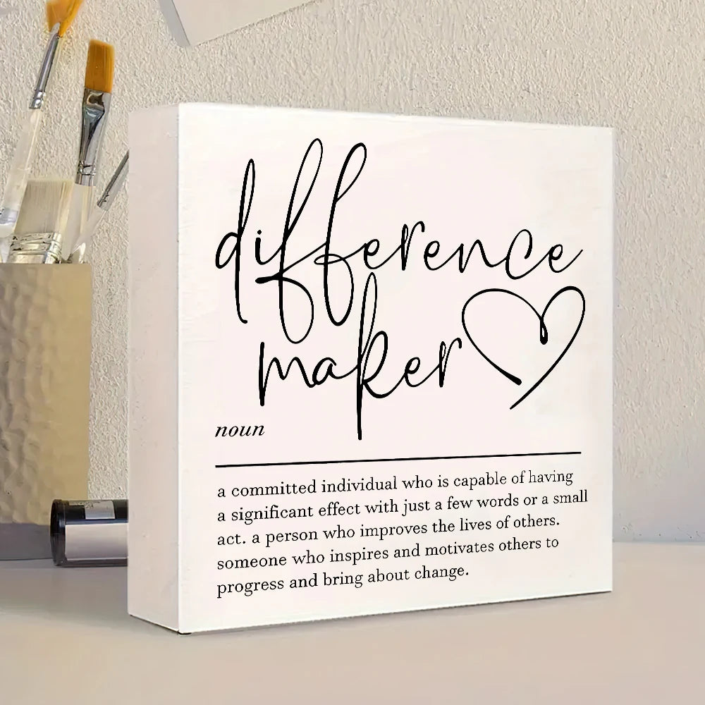 A white sign with black script reading difference maker and a definition below it.