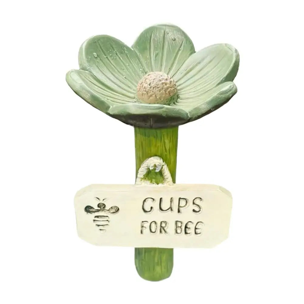 A green flower-shaped watering station with a bee on the center and a tag that reads Gups for Bee