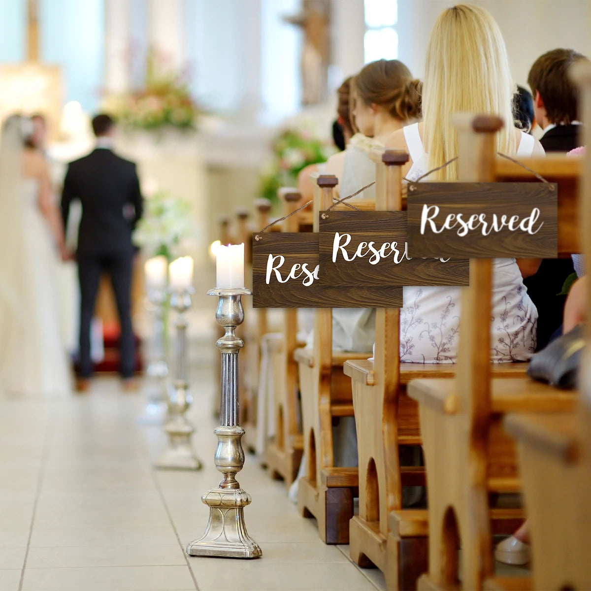 A row of wooden chairs for a wedding ceremony with rustic reserved signs on the back.