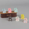 A collection of six colorful 3D resin animal keychains, including pink, blue, and yellow cats, displayed in front of a wooden