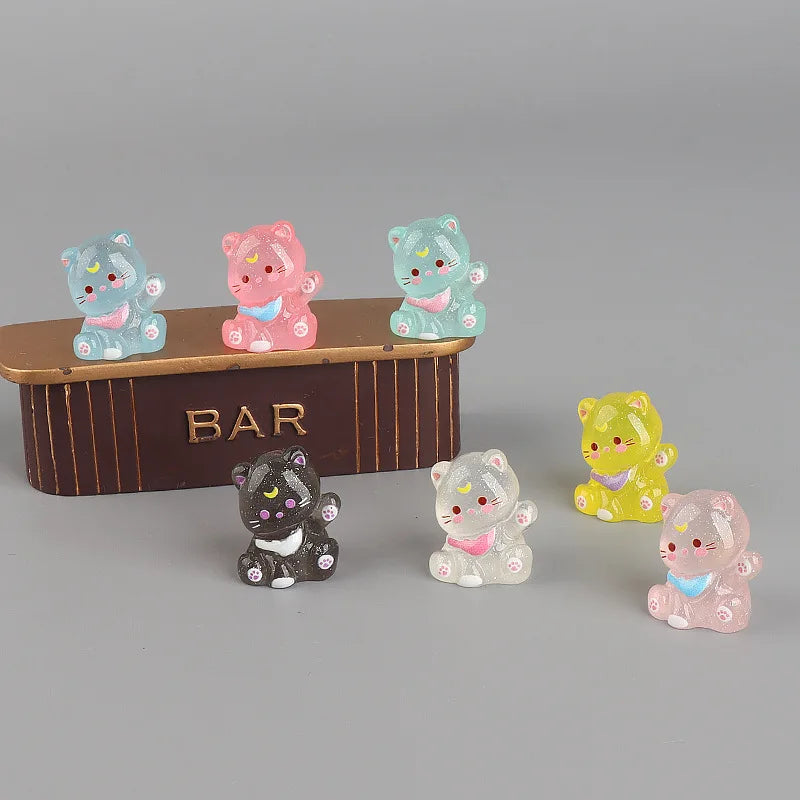 A collection of six colorful 3D resin animal keychains, including pink, blue, and yellow cats, displayed in front of a wooden