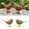 A pair of rustic metal bird sculptures in brown and gold colors displayed on a stone surface.