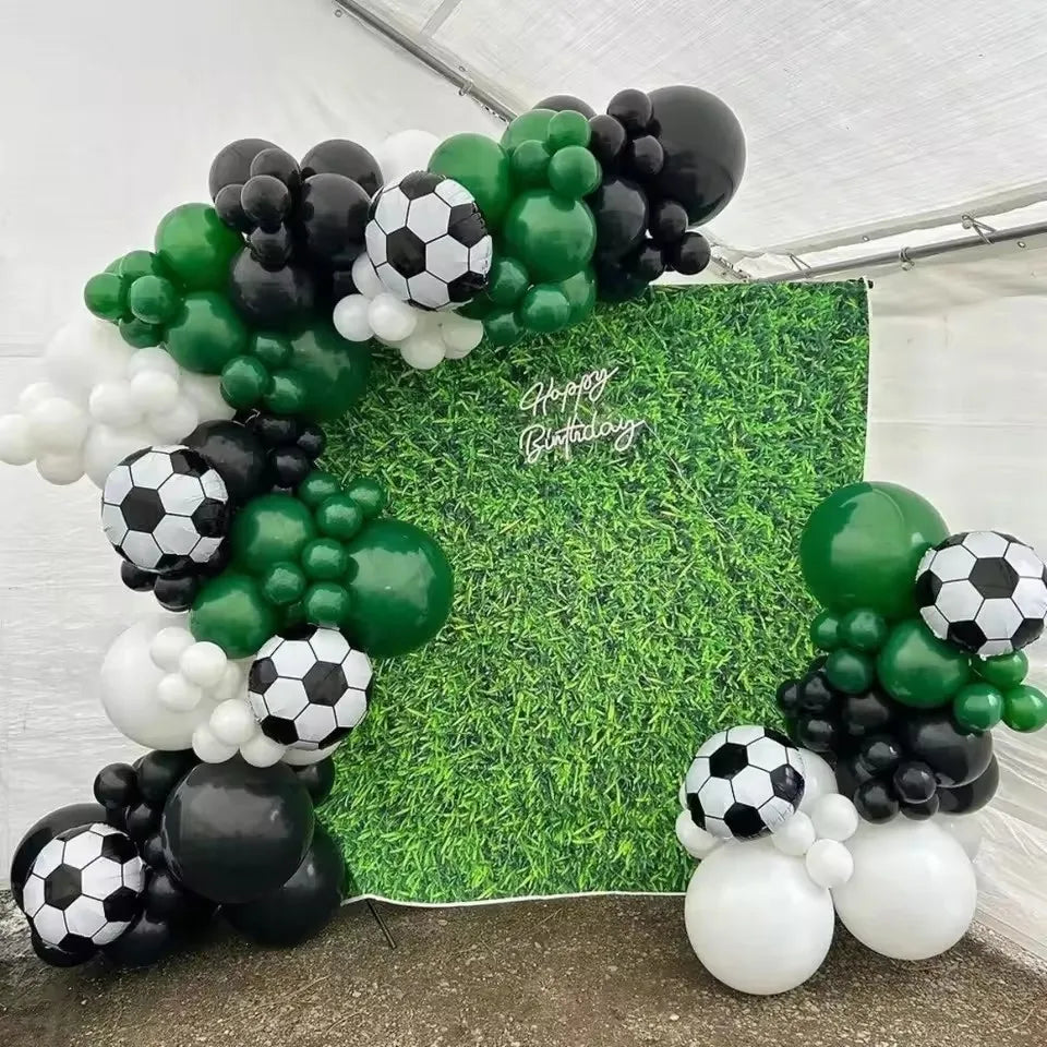 A balloon garland arch featuring black, white, and green balloons arranged in a soccer theme.