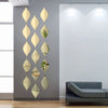 A vertical arrangement of ten reflective acrylic droplet mirror stickers in gold and green tones mounted on a gray wall.