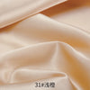 Close-up of smooth beige satin fabric draped and folded to show texture and sheen.