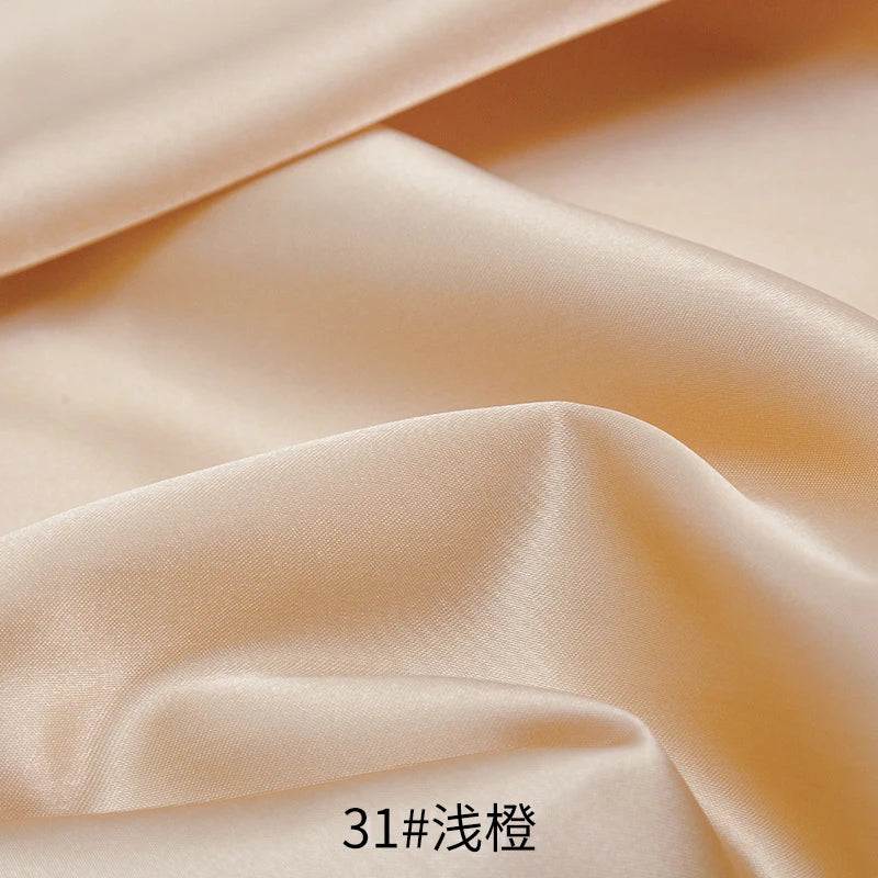 Close-up of smooth beige satin fabric draped and folded to show texture and sheen.