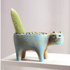 A ceramic planter shaped like a cat holding a green succulent plant.