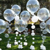 A collection of clear latex balloons floating above a green lawn.
