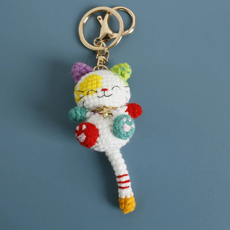 Handcrafted crochet cat keychain pendant with purple and yellow fur and a gold ring.