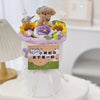 A handmade crochet flower bouquet featuring purple and yellow flowers arranged on a white stand.