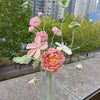 Un ramo de flores de ganchillo hecho a mano en tonos rosa y verde, exhibidas en un jarrón de vidrio.