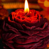 Nahaufnahme einer tiefroten handgemachten Rosen-Päonie-Blüten-Sojawachs-Kerze mit einer leuchtenden Flamme.