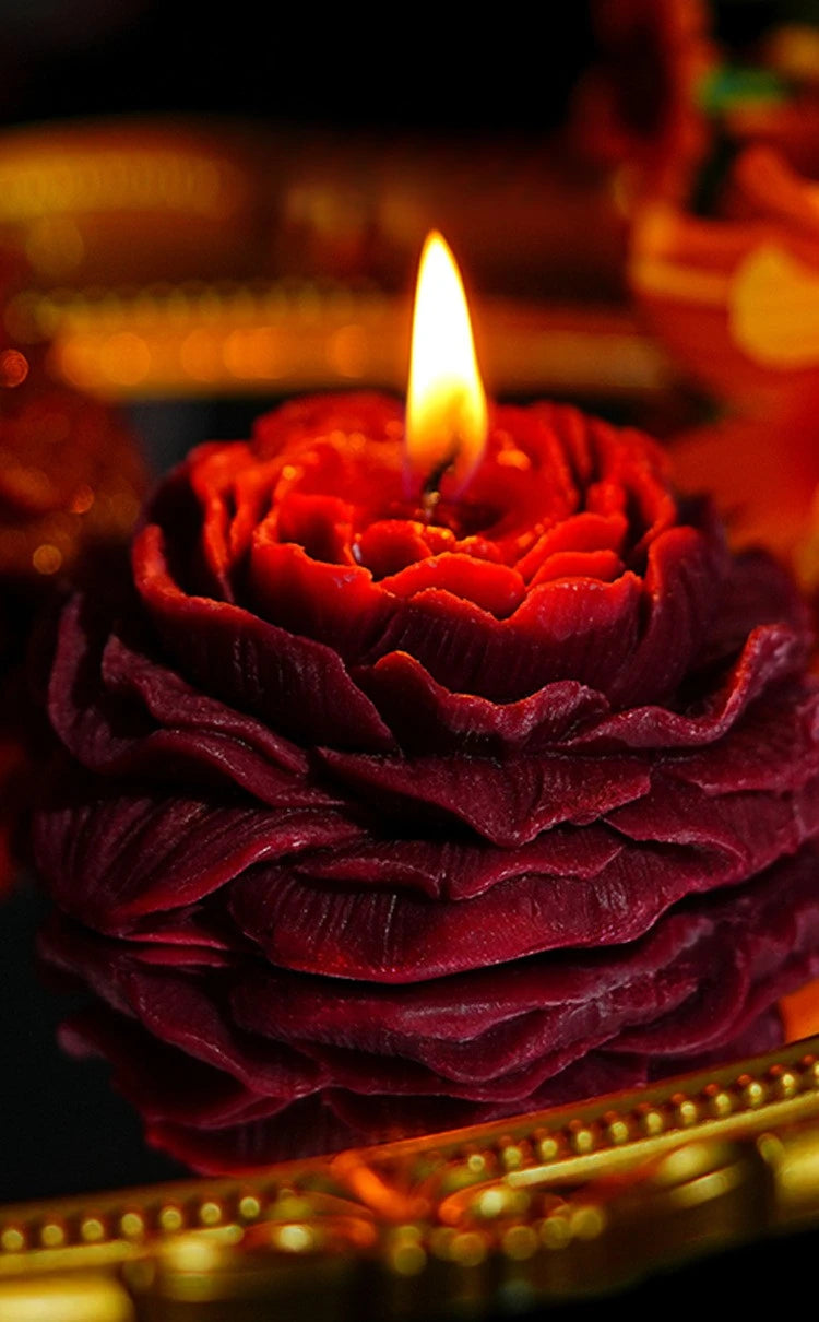 Nahaufnahme einer tiefroten handgemachten Rosen-Päonie-Blüten-Sojawachs-Kerze mit einer leuchtenden Flamme.