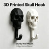A set of two 3D printed skull hooks, one black and one white, designed for a sturdy wall mount.