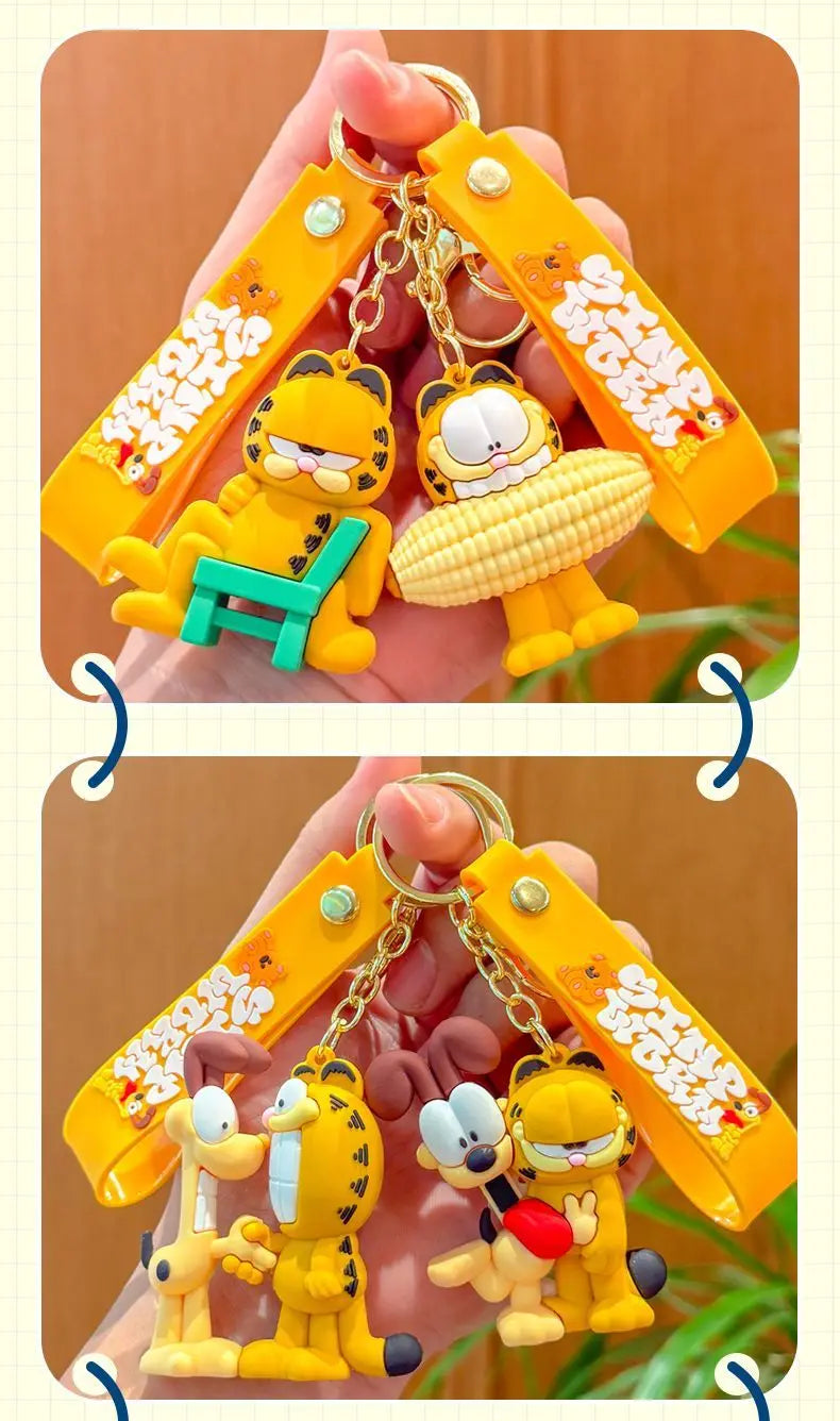 A hand holds an orange and yellow cartoon keychain pendant featuring Garfield and another character.