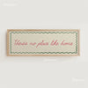 A framed canvas print with a light background and green border featuring the text There's no place like home in pink script.