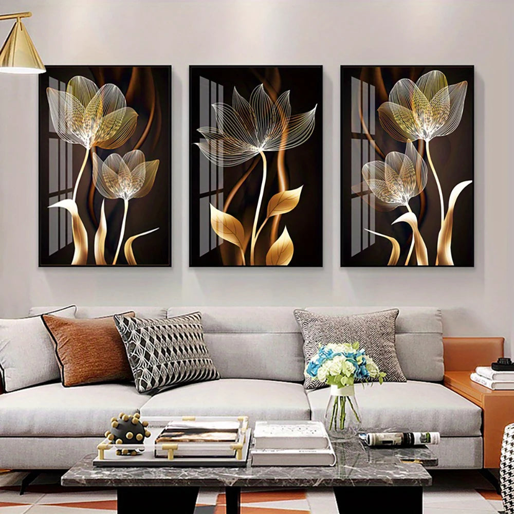 A set of three abstract flower canvas wall art pieces featuring golden and silver tones displayed on a modern living room wal