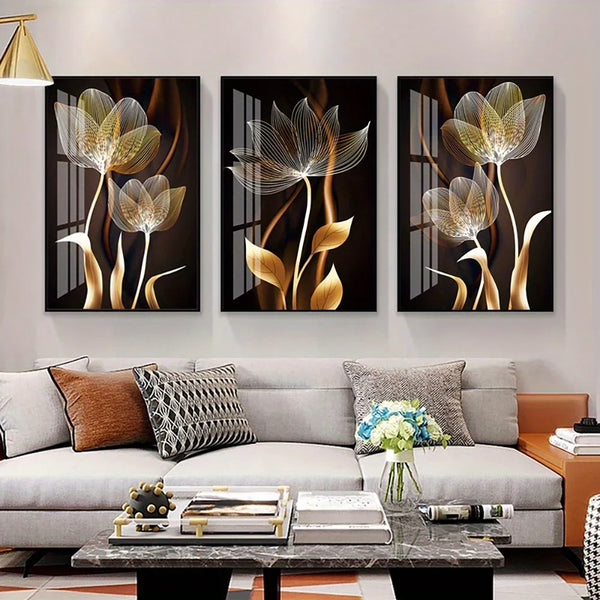 Un conjunto de tres piezas de arte en lienzo abstracto con tonos dorados y plateados, exhibidas en una sala de estar moderna