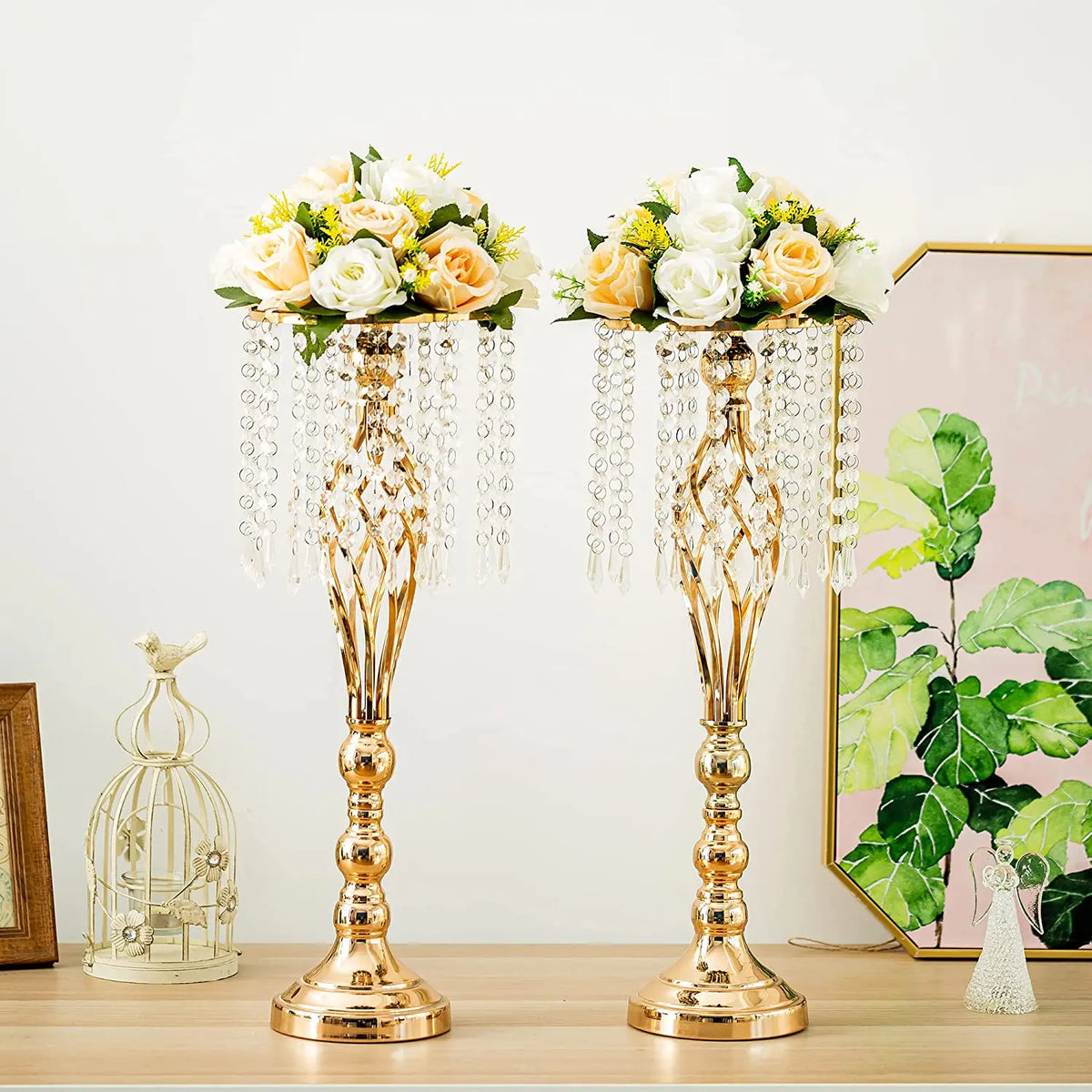 A set of gold crystal vases with floral arrangements displayed on a wooden table.