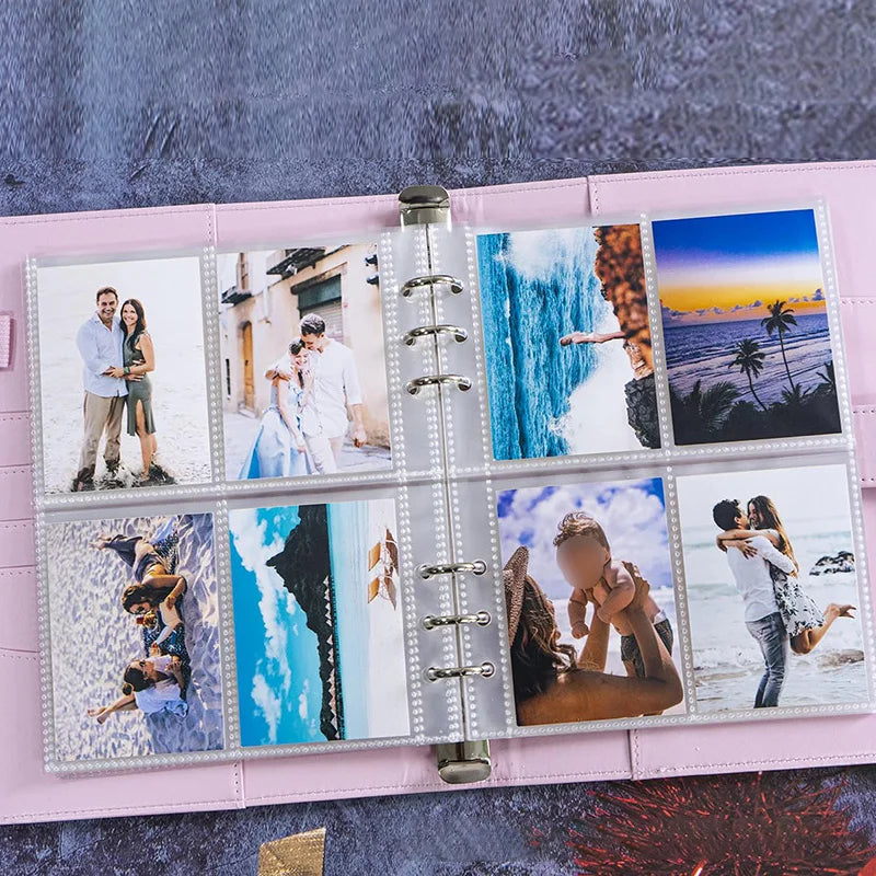 A pink binder holding several glossy Kpop photocards featuring people and landscapes.