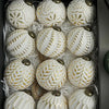 A collection of twelve white and gold patterned retro shatterproof Christmas tree ball ornaments displayed in a box.