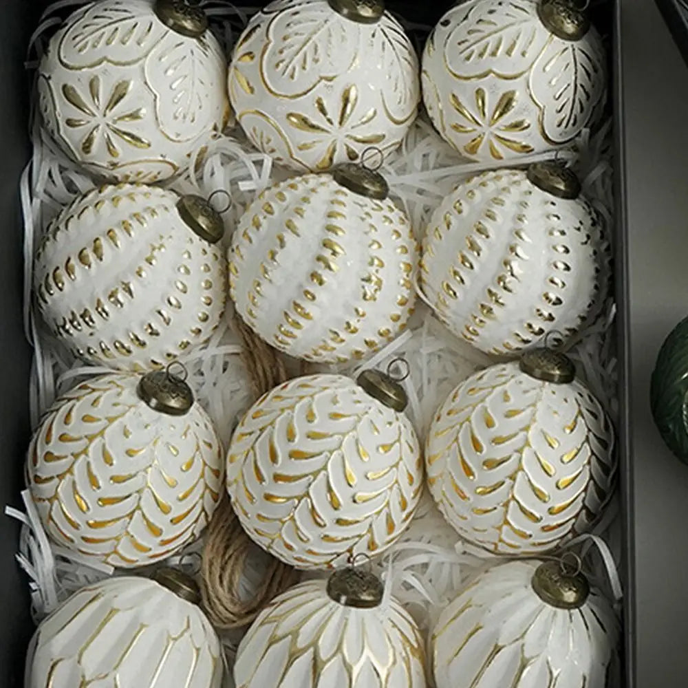 A collection of twelve white and gold patterned retro shatterproof Christmas tree ball ornaments displayed in a box.