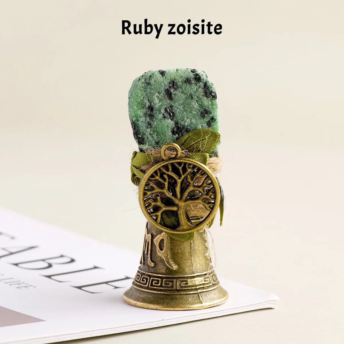 A natural crystal ruby zoisite specimen mounted on a brass bell with a copper finish.