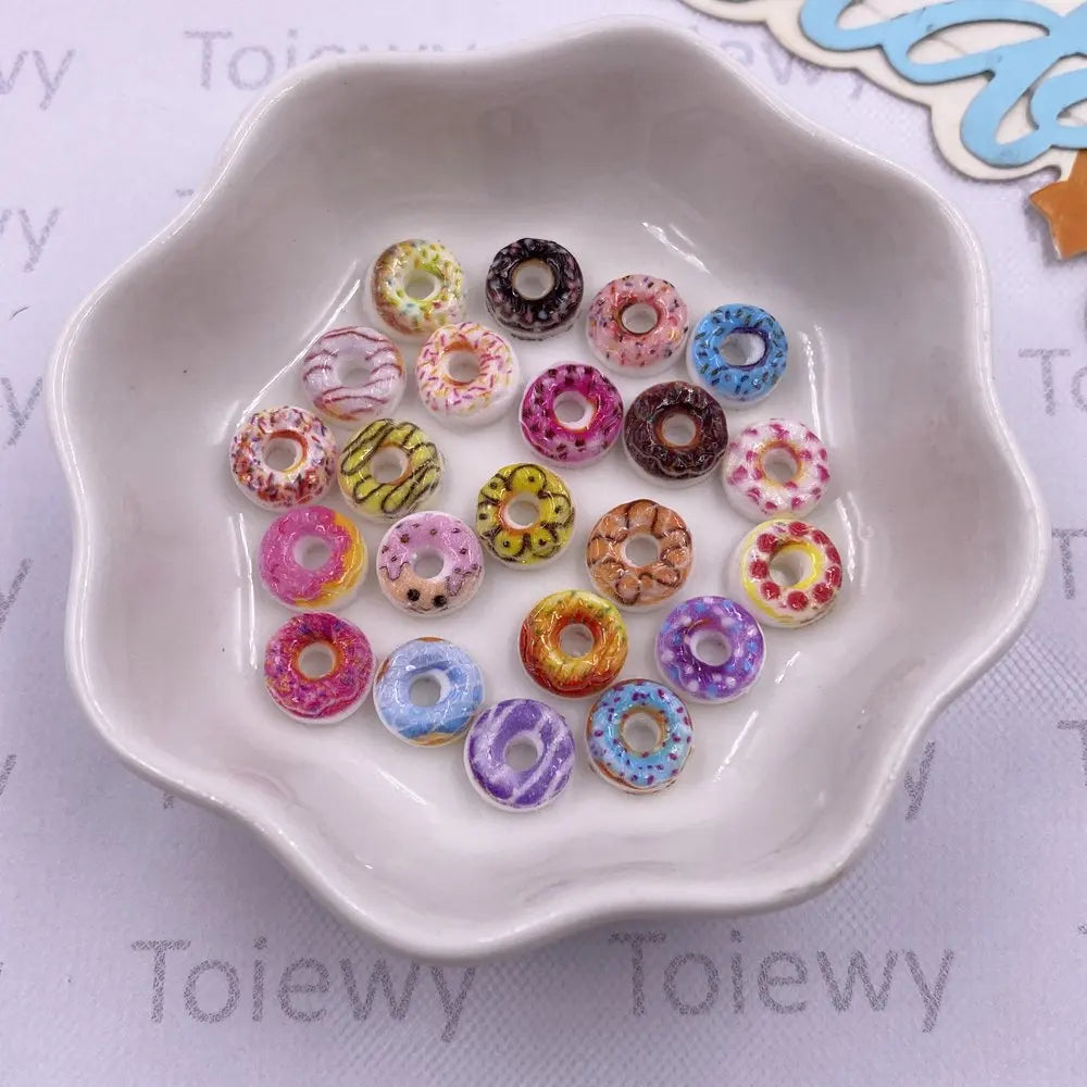 A white dish filled with 20 colorful resin cheese and donut nail art charms.